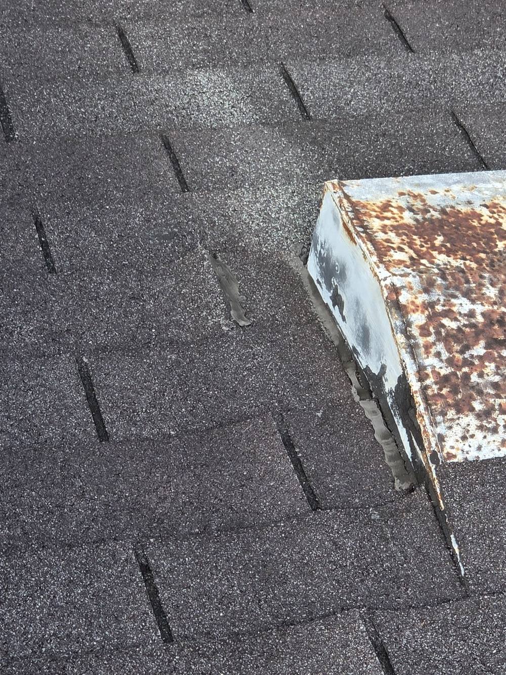 A rusted roof vent with its seal pulling away from the shingles